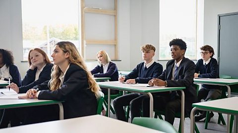 High school students in uniform sit at their school desks 