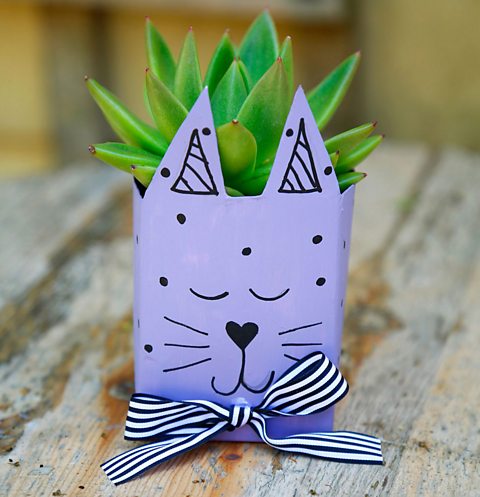 A purple animal vase with a plant in it