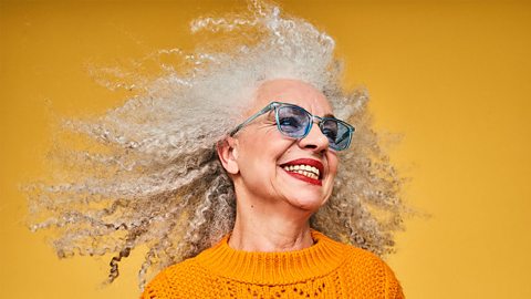 Smiling lady with long and curly grey hair