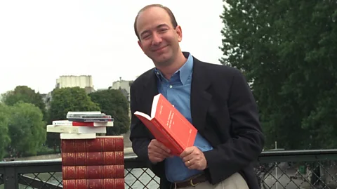 Getty Images Jeff Bezos standing next to stack of books (Credit: Getty Images)