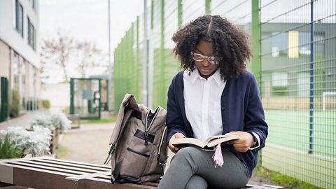 Girl sitting on a bench outside and reading a book