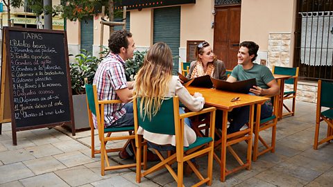 Two couples sitting at a table, outside a restaurant.