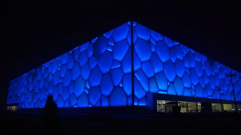 The Water Cube lit up in blue lights at night 