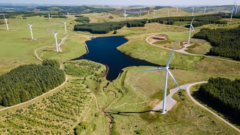 A wind farm with many large white wind turbines spread across a grassy landscape.