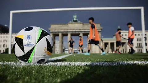 Getty Images Artificial grass, like this pitch in front of Berlin's Brandenburg Gate prior to the UEFA Euro 2024 Championships, can degrade over time into microplastics (Credit: Getty Images)