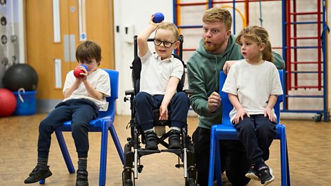 Three children are playing boccia at school with teacher