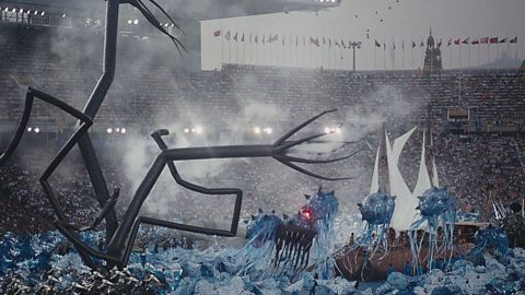 A wooden ship in a staged storm, with an inflatable sea monster in front of it.