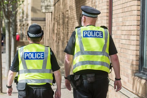 Woman and man police officers in walking on the street in Edinburgh.