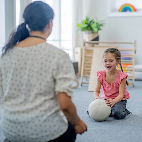 young girl plays with a soft ball at home