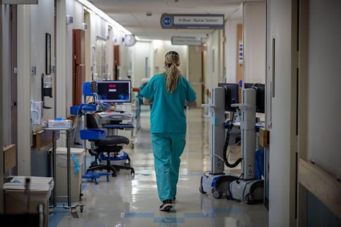 A practical nursing specialist walking down hospital hallway in USA.