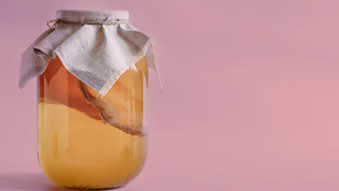 Getty Images A bottle of kombucha against a pastel pink background (Credit: Getty Images)