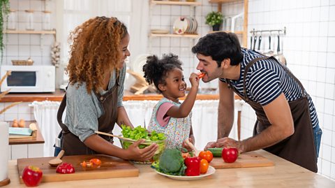 A family making a salad together with colourful fruit and vegetables