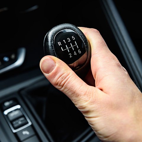 Close-up hand on a traditional manual car gear stick, article for learning to drive