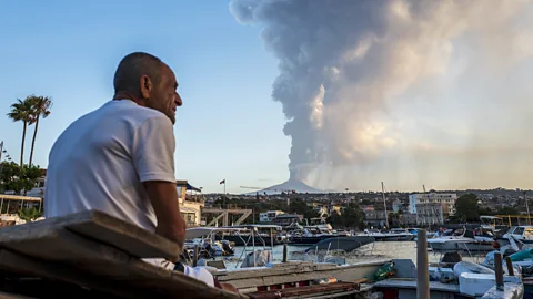 Getty Images A fisherman observing the eruption of Mount Etna on 4 August 2024 (Credit: Getty Images)