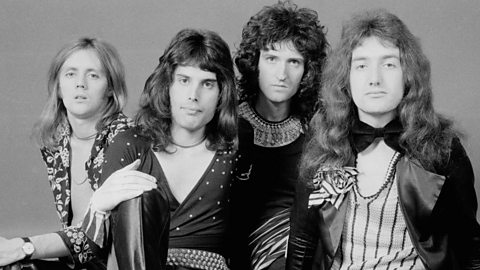 A black and white photograph of four males posing in a casual seated group.  