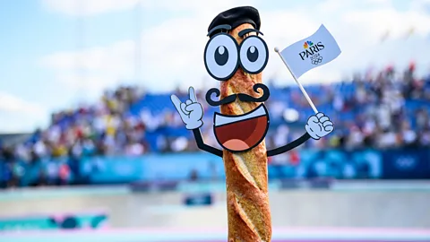 Getty Images A baguette with animated facial features, wearing a beret and holding a Paris Olympics 2024 flag (Credit: Getty Images)