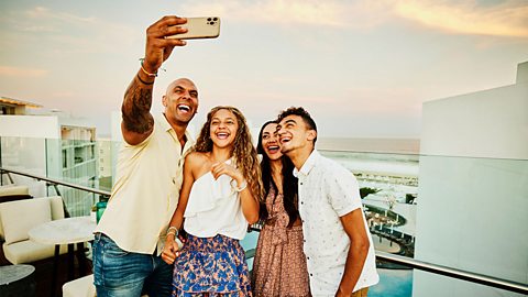 Smiliing family taking selfie on hotel balcony