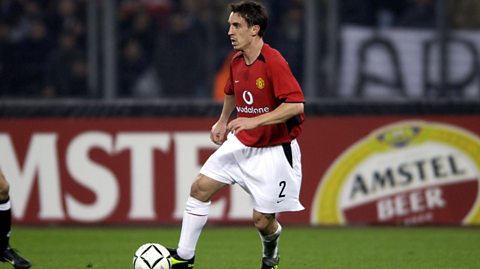 Gary Neville dribbles with the football in a Manchester United kit