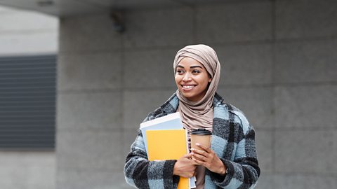 Smiling female student wearing a hijab and carrying some books