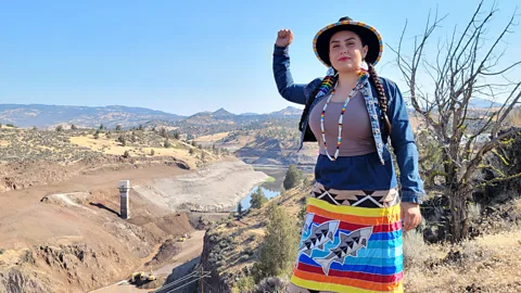 Brook Thompson Brook Thompson stands above the Klamath River, with her fist raised (Credit: Brook Thompson)