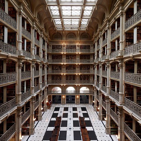 Atrium of a rectangular library with black and white marble flooring, five floors of iron balconies and a large skylight