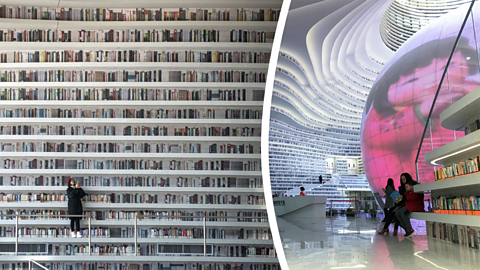 A view of the floor-to-ceiling white bookshelves with a woman in a dark coat stood on the walkway, alongside a woman and child reading in front of a large glowing sphere