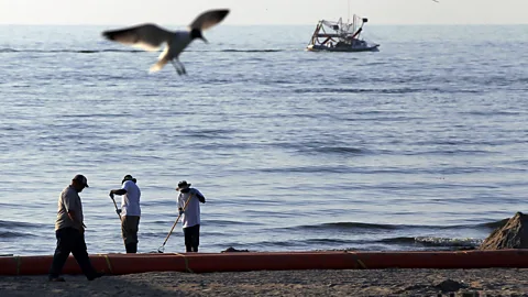 Getty Images Trabalhadores tentam limpar uma praia contaminada por óleo em Grand Isle, Louisiana, junho de 2010 (Crédito: Getty Images)