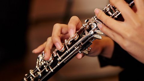 A close up photo of hands playing an oboe.