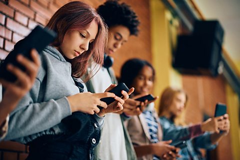 A group of teenagers look at their mobile phones