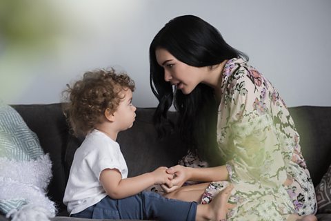 A mum talking to her son on the sofa.