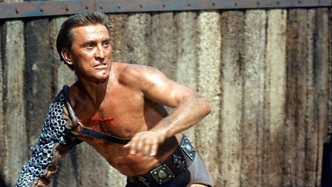 Actor Kirk Douglas, with a scar on his chest as he impersonates an ancient gladiator.