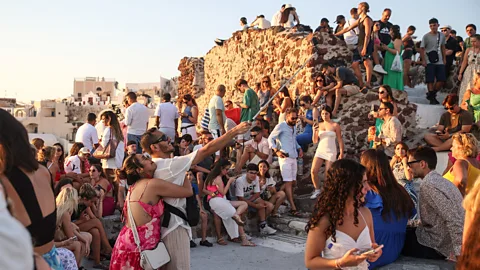 Getty Images Crowds of tourists watching the sunset in Oia, Santorini (Credit: Getty Images)