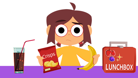 A puzzled young girl holding a packet of crisps and a banana, next to her is a glass of fizzy pop and a lunchbox