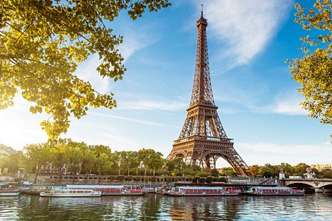 Eifel Tower from below with trees and river in foreground