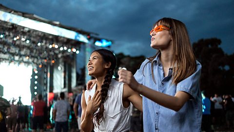 Two female friends dancing at an outside music concert
