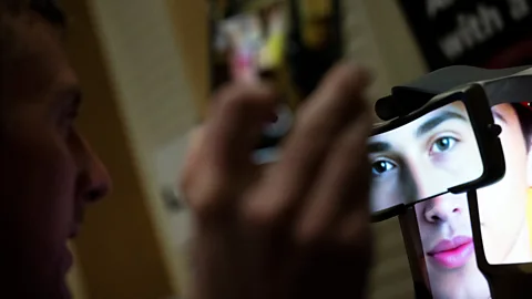 Getty Images A man talks to a screen showing an AI companion's face (Credit: Getty Images)