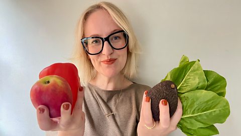 Lauren holding an apple, red pepper, avocado and salad leaves