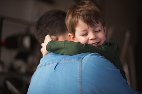 Young boy hugging his father.