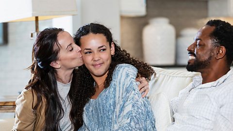 Girl sitting on sofa with her mum and dad
