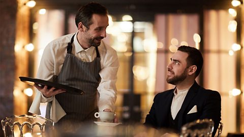Waiter serving coffee to a seated man