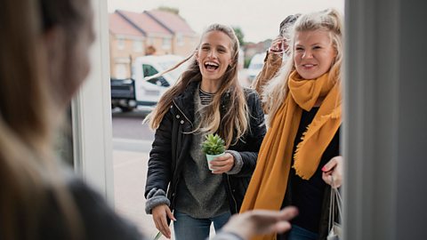 A woman opening the door to her neighbours