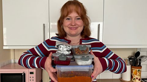 Izzie Cox holding four filled food containers and two breakfast wraps which are in foil