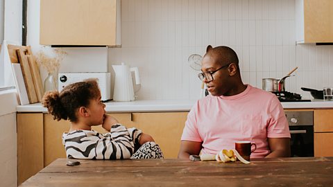 A father and daughter have a discussion at the table.