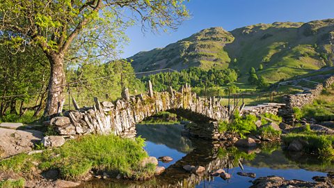 A stone bridge in the Lake District, surrounded by hills and trees