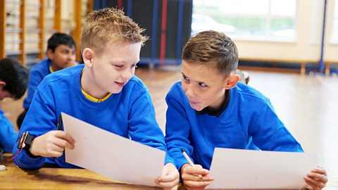 Two children comparing designs in a classroom.