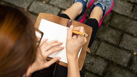 A view from above as a young woman writes in a journal