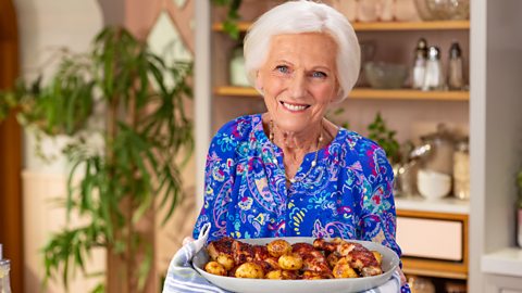 Mary Berry holding a serving dish full of roast potatoes