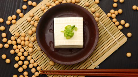 A bowl of tofu surrounded by soy beans