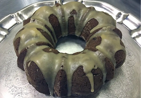 A dark ring shaped cake with a drizzle icing 