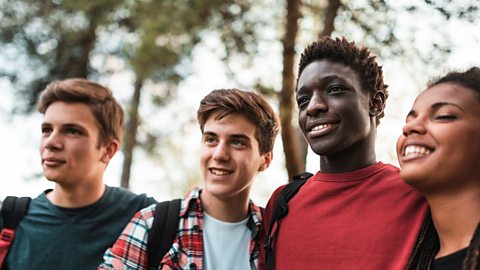 Three male teenagers and one female teenager smiling and standing together